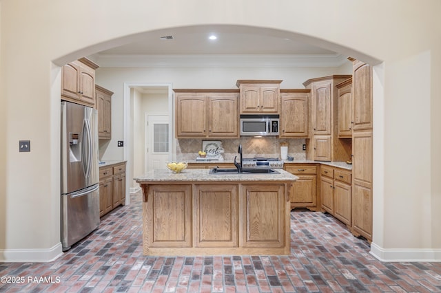 kitchen with sink, crown molding, stainless steel appliances, tasteful backsplash, and an island with sink