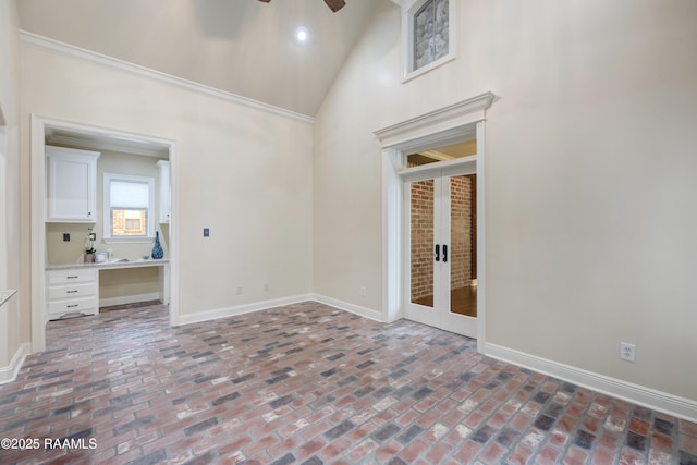 empty room with ornamental molding, high vaulted ceiling, ceiling fan, and french doors