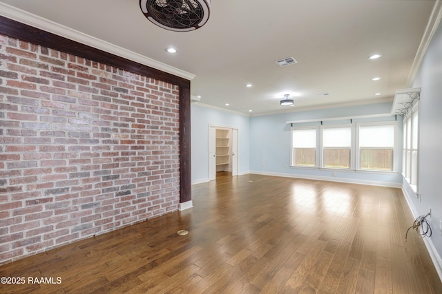 unfurnished living room with crown molding, brick wall, and hardwood / wood-style floors