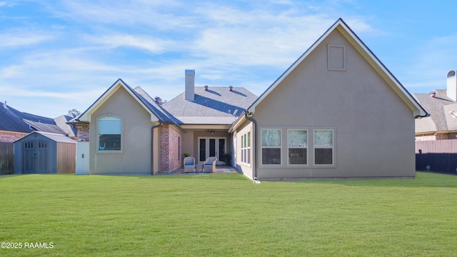 back of property with a yard, a patio, and a shed