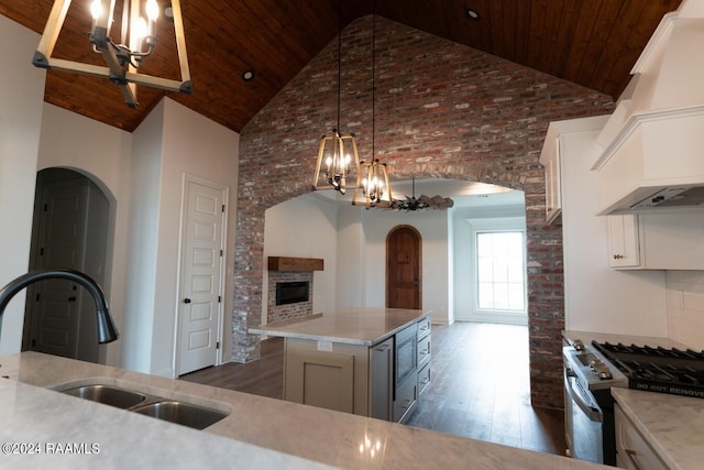 kitchen featuring a center island, high vaulted ceiling, a chandelier, stainless steel stove, and custom exhaust hood