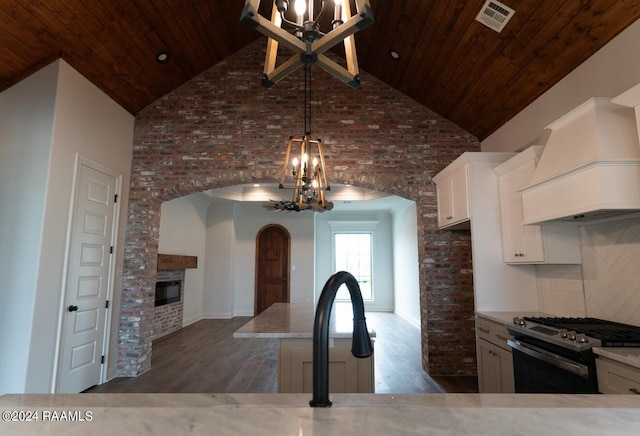 kitchen featuring stainless steel range oven, dark wood-type flooring, high vaulted ceiling, and an inviting chandelier