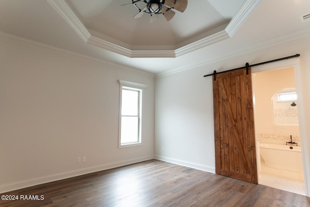 unfurnished bedroom featuring a barn door, wood-type flooring, crown molding, and ensuite bath