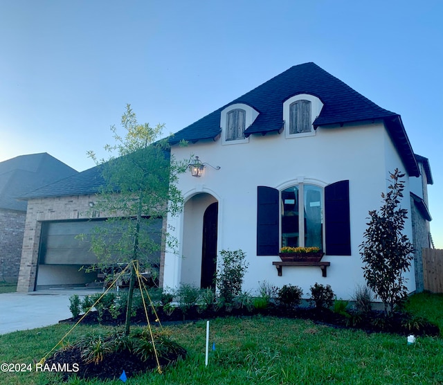 french country inspired facade with a front yard and a garage