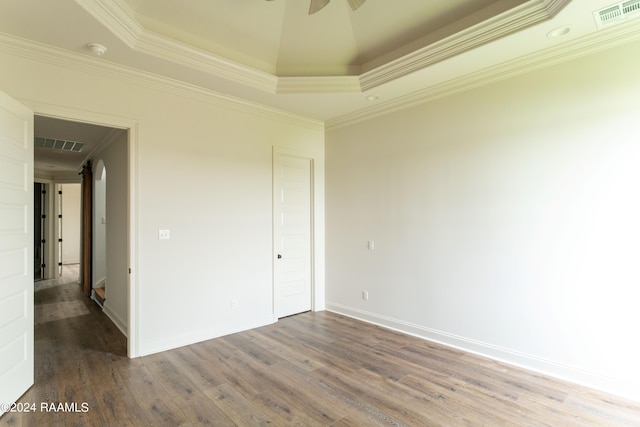 unfurnished room featuring a raised ceiling, crown molding, hardwood / wood-style floors, and ceiling fan