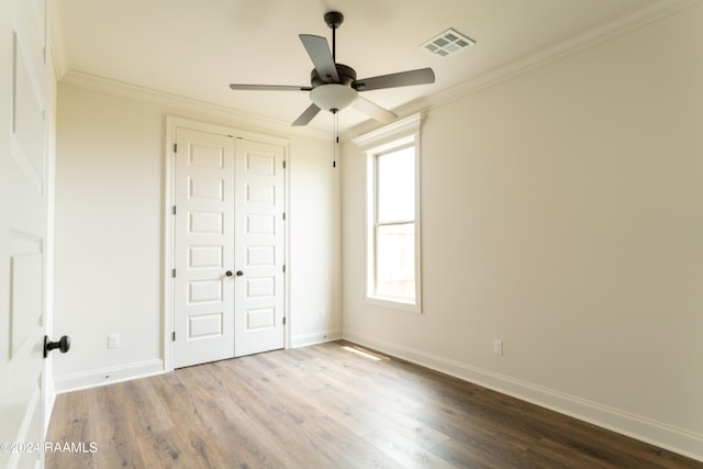 unfurnished bedroom featuring crown molding, a closet, ceiling fan, and light wood-type flooring