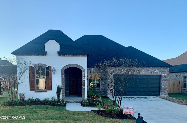 french country style house with a garage and a front lawn