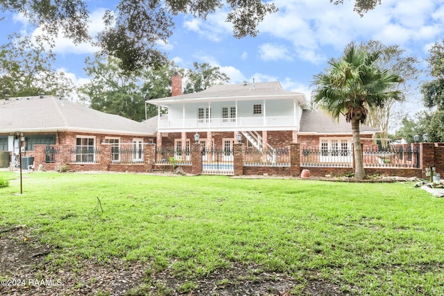 rear view of property featuring a lawn and cooling unit