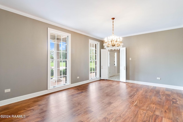 unfurnished room featuring hardwood / wood-style floors, a chandelier, and ornamental molding