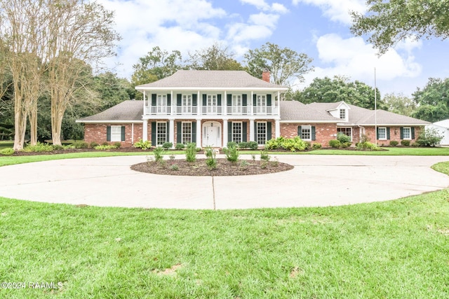 colonial-style house with a front yard and a balcony