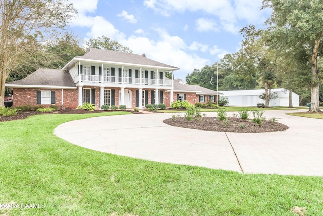 colonial-style house with a front yard and a balcony