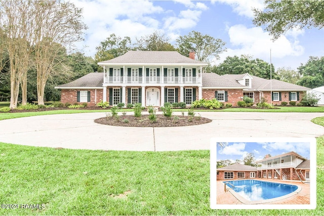 view of front of property featuring a front yard, a balcony, and a patio area