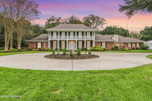 13933 Pumping Plant Rd, Abbeville, LA 70510 - view of front of home with curved driveway, a balcony, a yard, brick siding, and a chimney