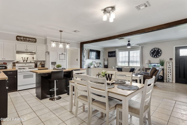 tiled dining area featuring beam ceiling, ceiling fan, and ornamental molding