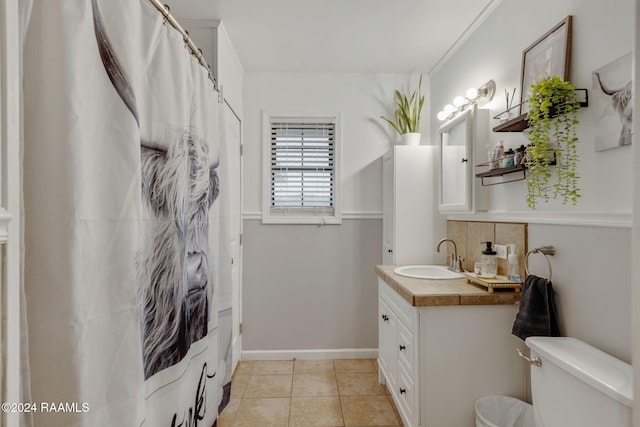 full bathroom featuring tile patterned flooring, backsplash, crown molding, toilet, and vanity