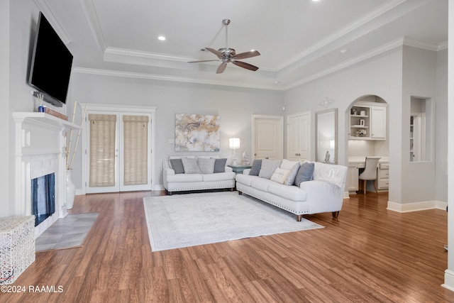 unfurnished living room with a towering ceiling, a raised ceiling, ceiling fan, crown molding, and hardwood / wood-style flooring