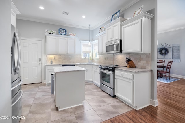 kitchen with white cabinets, stainless steel appliances, crown molding, and light hardwood / wood-style floors