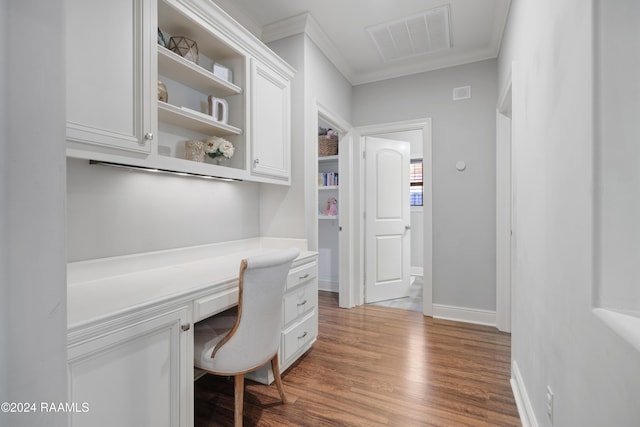 office area with built in desk, crown molding, and dark wood-type flooring