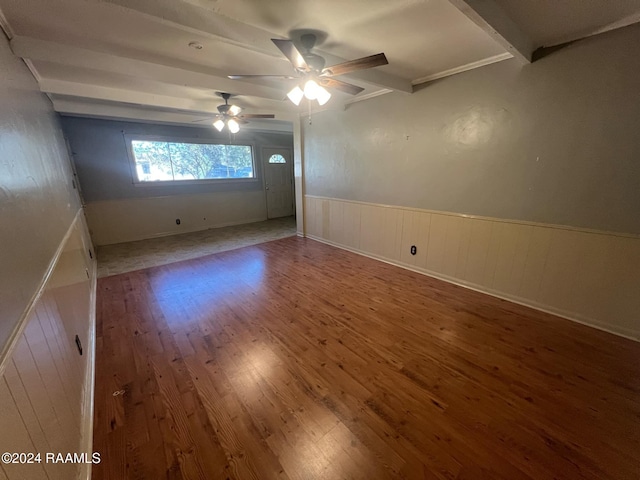 unfurnished room with ceiling fan, beamed ceiling, wooden walls, and hardwood / wood-style floors