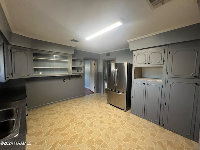 kitchen with gray cabinetry, stainless steel refrigerator, and sink