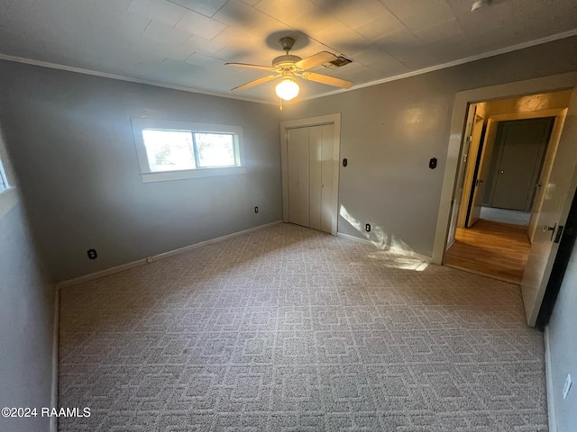 empty room with ceiling fan, crown molding, and carpet flooring