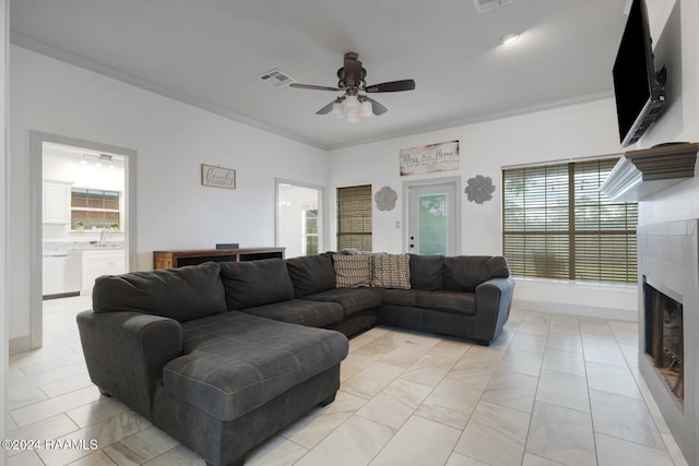 living room with sink, light tile patterned floors, ceiling fan, and crown molding