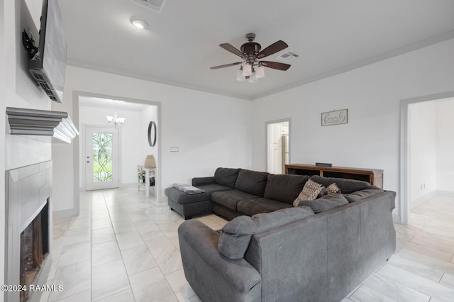 living room with ornamental molding, ceiling fan with notable chandelier, and a tiled fireplace