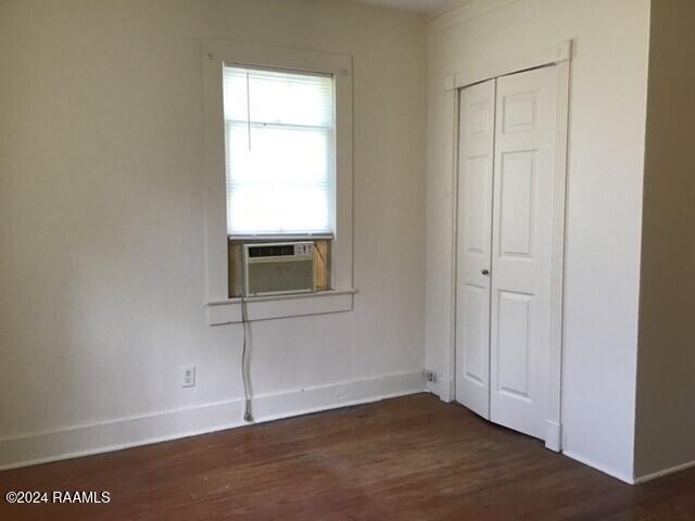 unfurnished bedroom featuring a closet, cooling unit, and dark wood-type flooring