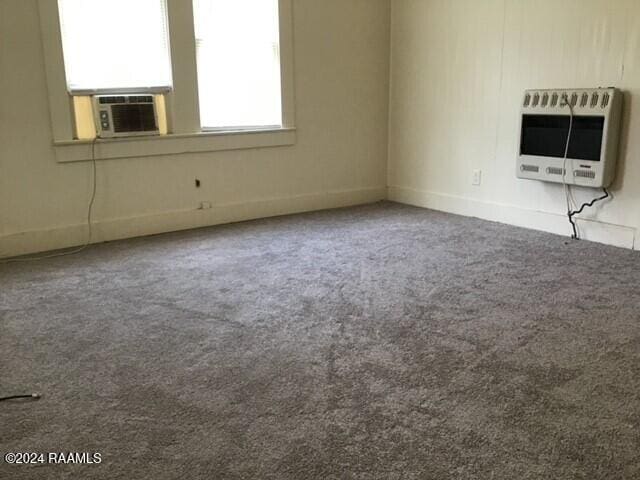 spare room with carpet flooring, heating unit, and cooling unit