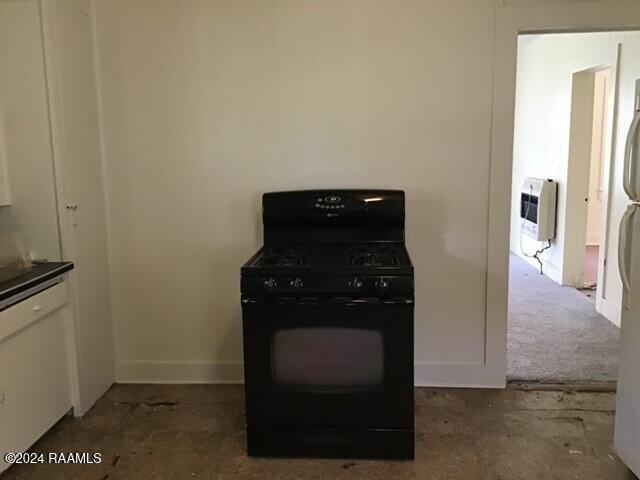 kitchen featuring heating unit, white cabinetry, and black gas stove