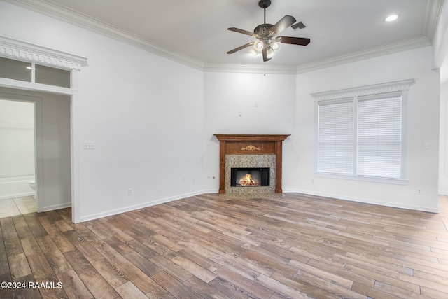 unfurnished living room featuring light hardwood / wood-style floors, crown molding, a premium fireplace, and ceiling fan