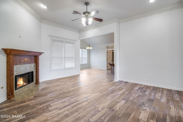 unfurnished living room featuring a premium fireplace, hardwood / wood-style floors, crown molding, and ceiling fan