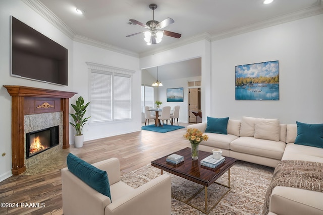 living room with a premium fireplace, ornamental molding, wood-type flooring, and ceiling fan