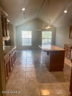 kitchen with a kitchen breakfast bar, lofted ceiling, a center island, and tile patterned flooring