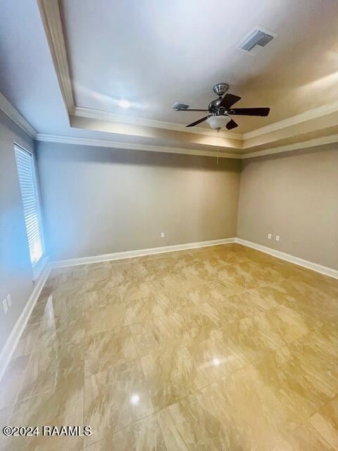 spare room featuring crown molding, ceiling fan, and a raised ceiling