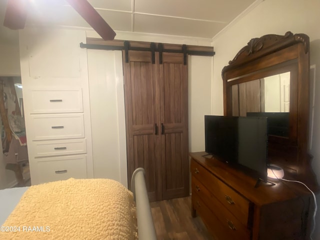 bedroom with crown molding, a barn door, and dark hardwood / wood-style flooring