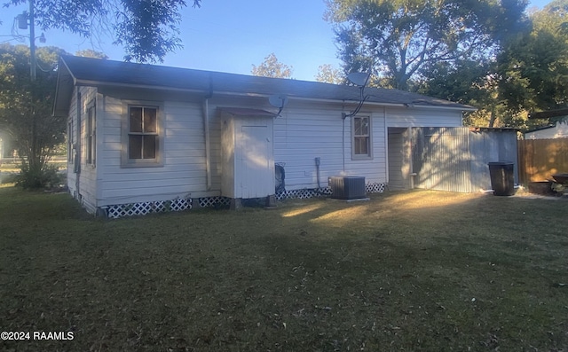 rear view of house with central air condition unit and a yard