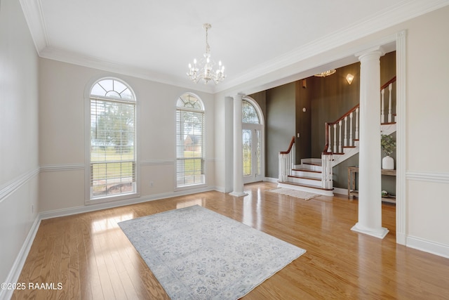 entryway with an inviting chandelier, ornamental molding, and ornate columns