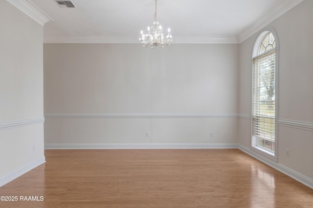 empty room with light wood-type flooring, a notable chandelier, and ornamental molding