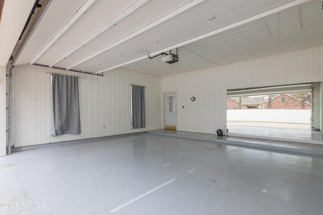 garage featuring a garage door opener and wooden walls