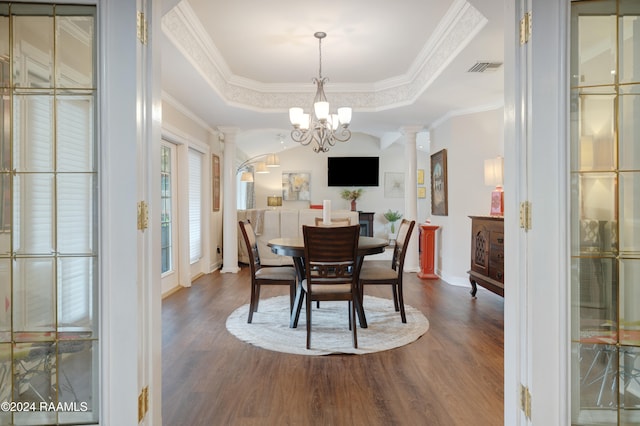 dining area with crown molding, a notable chandelier, dark hardwood / wood-style flooring, decorative columns, and a tray ceiling