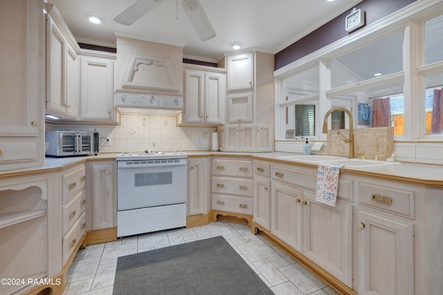 kitchen with light tile patterned flooring, backsplash, sink, white stove, and ceiling fan