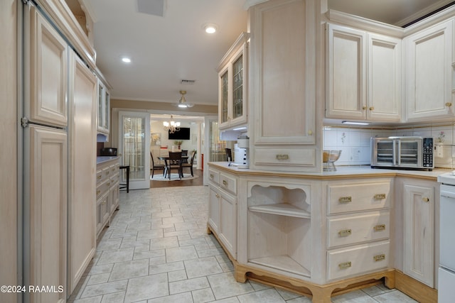 kitchen featuring backsplash, a chandelier, and crown molding