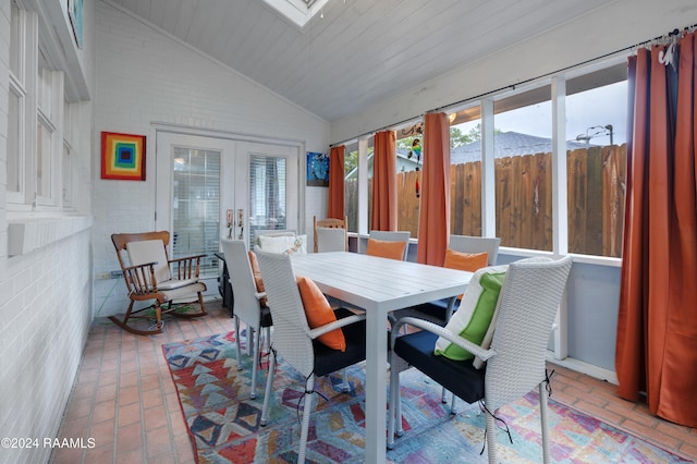 dining space featuring wooden ceiling, lofted ceiling with skylight, brick wall, and french doors