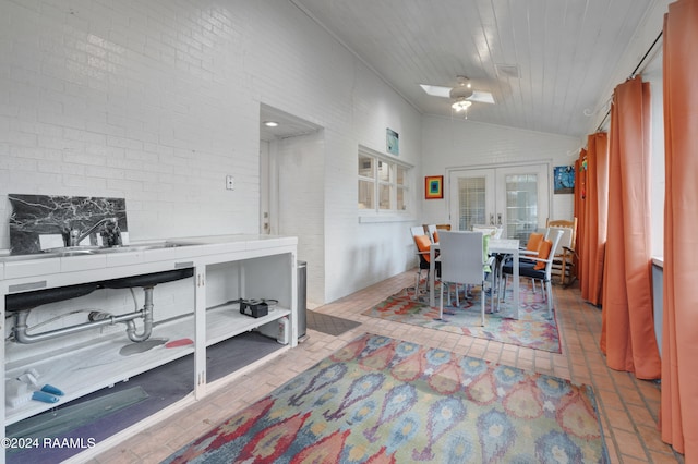 dining space featuring lofted ceiling, french doors, ceiling fan, and brick wall