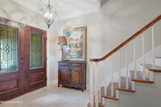 entrance foyer with ornamental molding and a chandelier