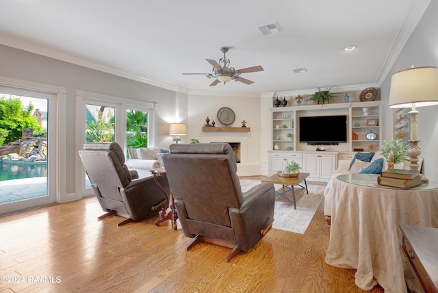 402 Old Settlement Rd, Lafayette, LA 70508 - living room with light wood finished floors, a ceiling fan, a fireplace with raised hearth, and ornamental molding