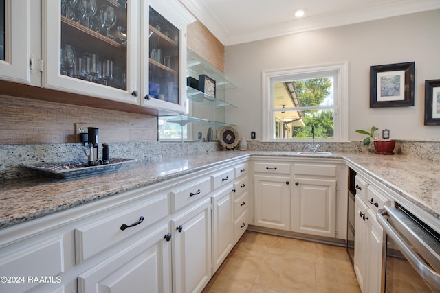 kitchen with light stone countertops, dishwasher, backsplash, white cabinetry, and ornamental molding