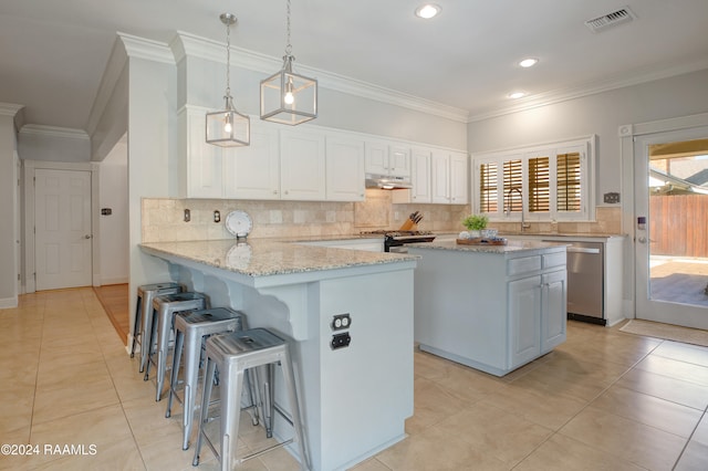 kitchen featuring kitchen peninsula, light stone counters, appliances with stainless steel finishes, white cabinetry, and decorative light fixtures