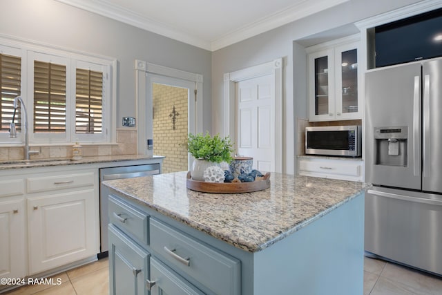 402 Old Settlement Rd, Lafayette, LA 70508 - kitchen featuring appliances with stainless steel finishes, a sink, light tile patterned floors, a center island, and light stone countertops